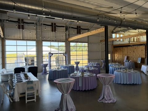 Main floor set for a reception, with string lights and three glass bay doors