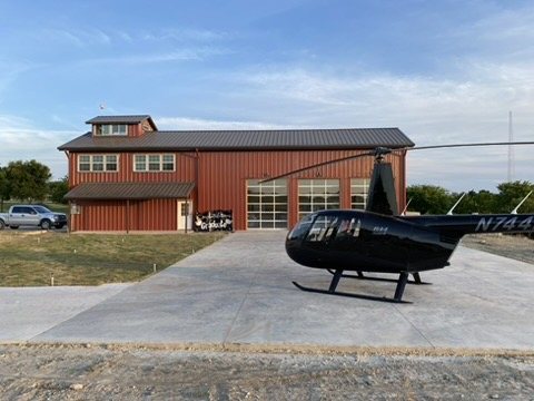 The Helo Station's red hangar with glass bay doors and the black helicopter on the landing pad