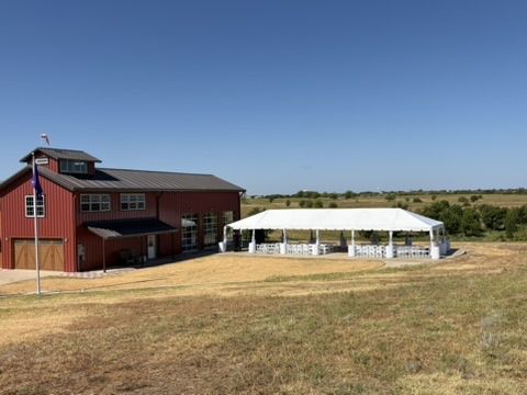 The red hangar and outdoor tent surrounded by open fields under a clear sky